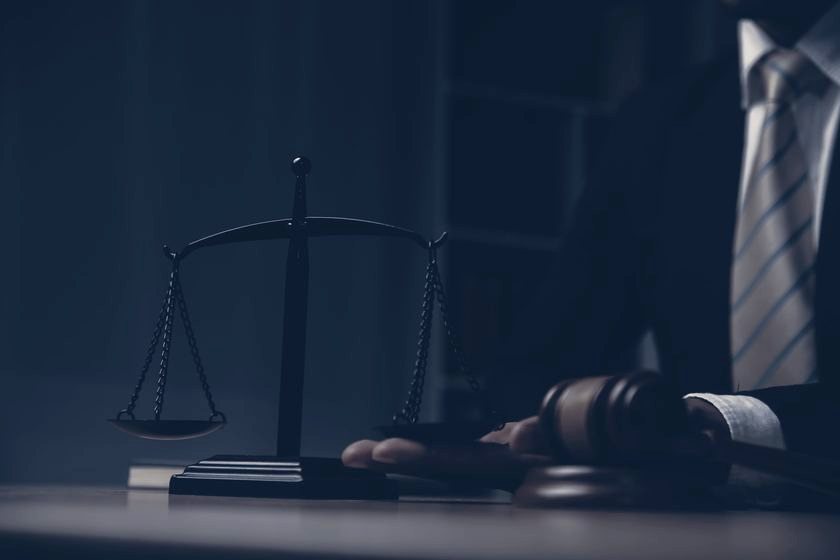 A judge's gavel and the scales of justice on a courtroom table
